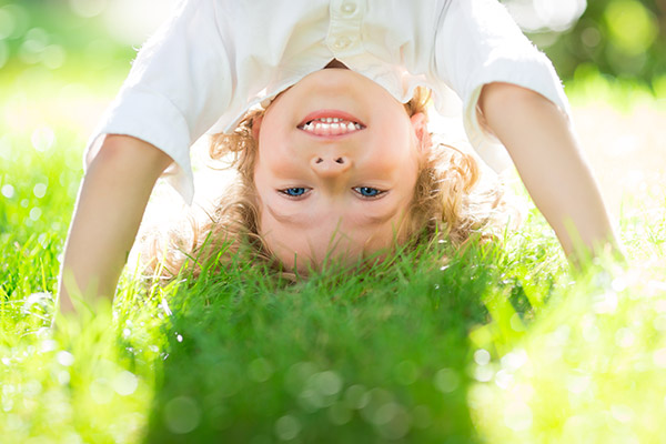 Child Having Fun Upside Down in Grass